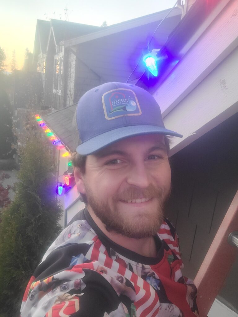 Dillon Bissel, owner of Homefront Holiday LIghts, smiling while installing a custom holiday lights display